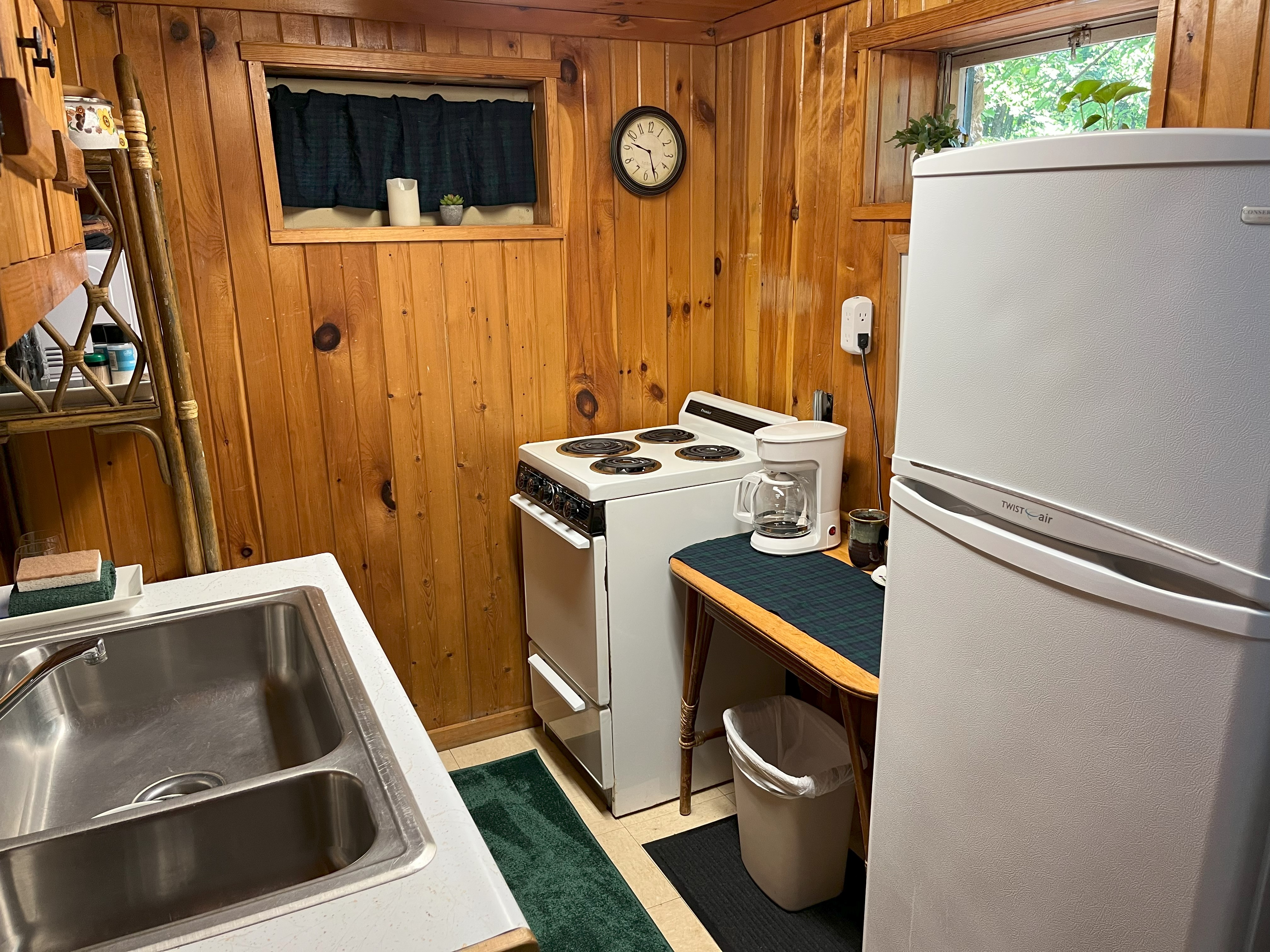 Cottage kitchenette with knotty pine walls, stove, and refrigerator
